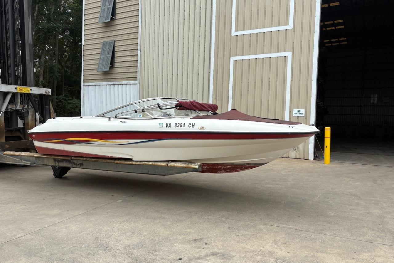 Bayliner 210 Classic 2001 Bayliner 210 Classic boat on forklift near warehouse entrance.