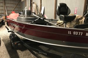 Lund 1675 Impact 2015 Lund 1675 Impact boat in storage, featuring a red exterior and trailer.