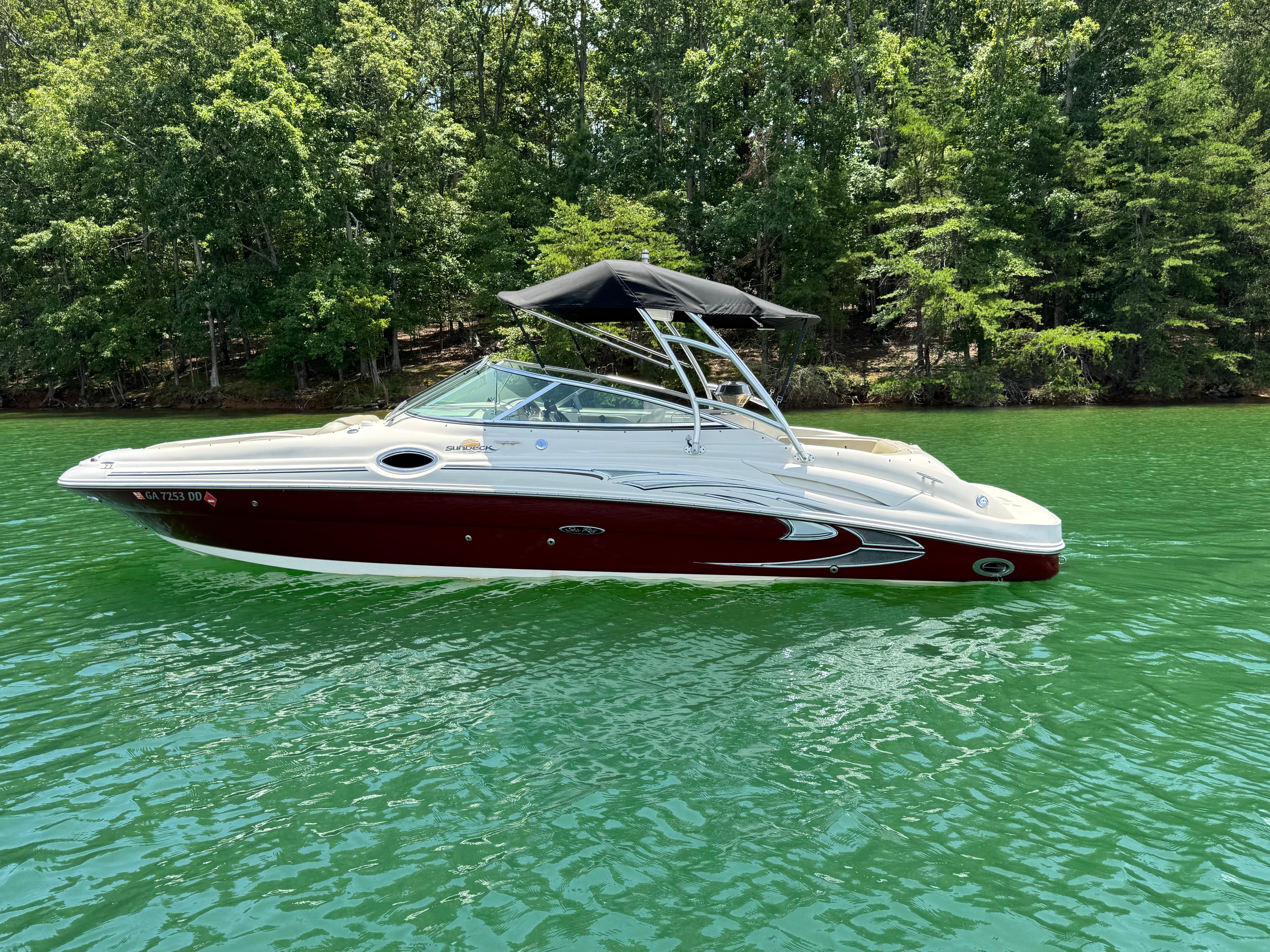 Sea Ray 270 Sundeck 2006 Sea Ray 270 Sundeck boat on a serene lake with lush green trees.