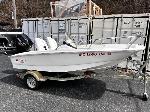Boston Whaler 130 Super Sport 2017 Boston Whaler 130 Super Sport boat on trailer, parked near shipping containers.