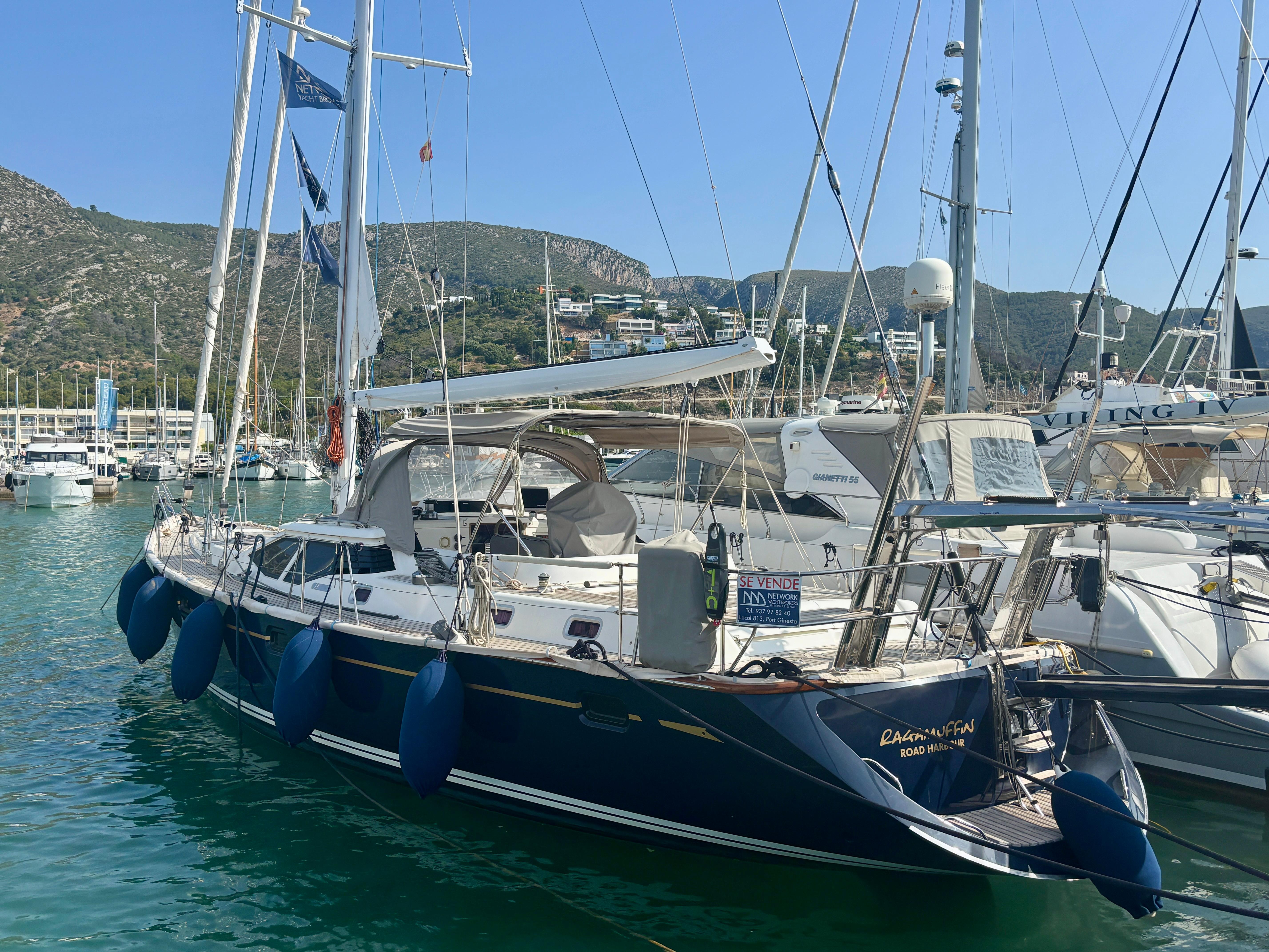 Oyster 56 Sailing yacht Oyster 56, 2003 model, docked in a marina with scenic mountain backdrop.