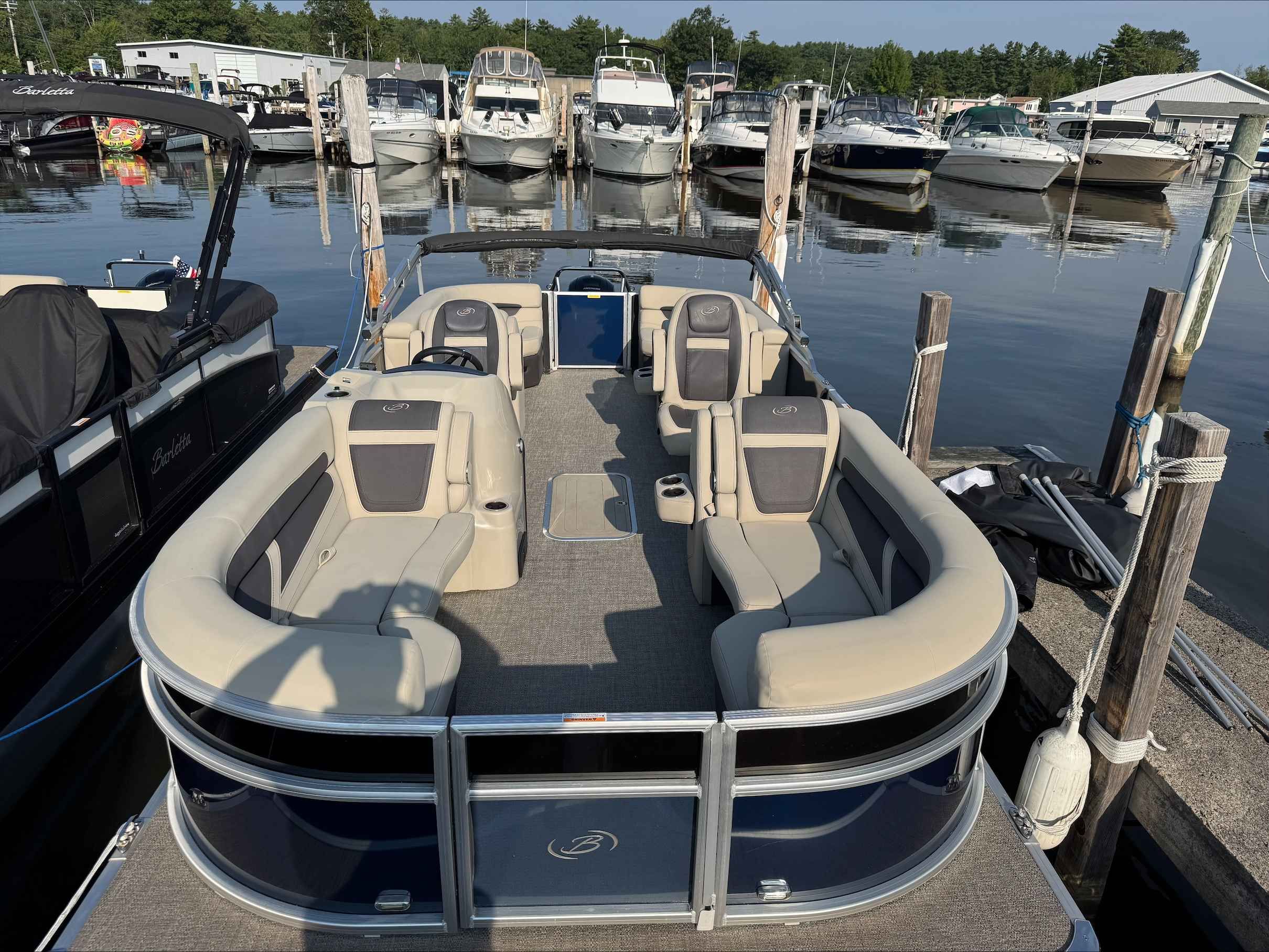 Barletta Cabrio 22QC 2022 Barletta Cabrio 22QC pontoon boat docked at marina with luxurious seating.