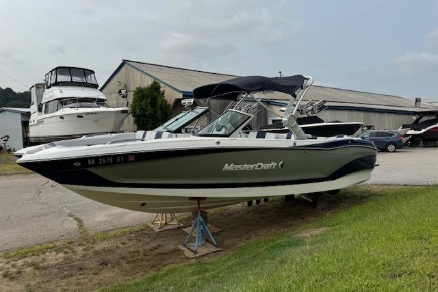 MasterCraft X26 2020 MasterCraft X26 boat on display outdoors near a marina.