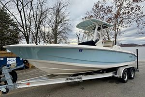 Boston Whaler 220 Dauntless 2022 Boston Whaler 220 Dauntless boat on trailer by a lake, surrounded by trees.