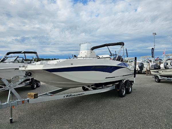 Starcraft SVX 211 OB CC 2025 Starcraft SVX 211 OB CC boat on trailer, displayed outdoors under cloudy sky.