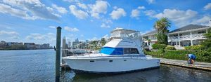 Bertram 38 Convertible 1982 Bertram 38 Convertible yacht docked by waterfront homes under a blue sky.