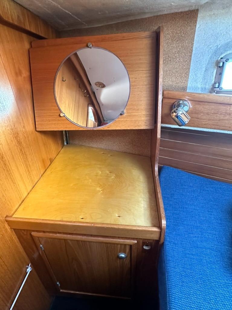 Jeanneau Voyage 11.20 Wooden interior of 1990 Jeanneau Voyage 11.20 sailboat with mirror and blue cushion.