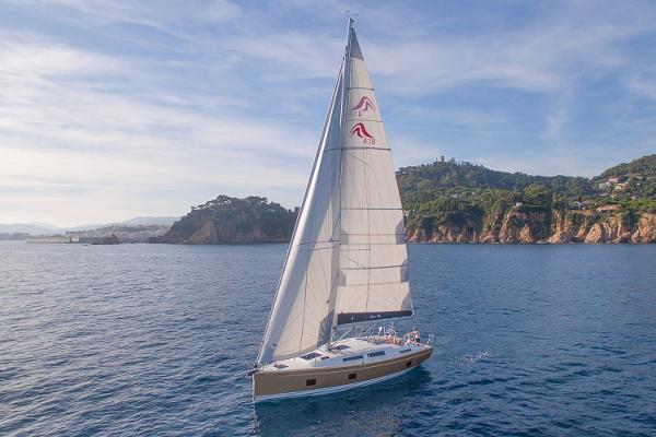 Hanse 418 2025 Hanse 418 sailboat cruising near scenic coastline under clear skies.