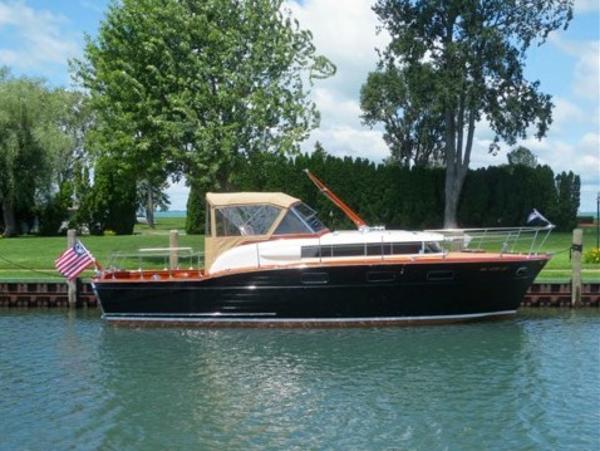 Chris-Craft 33 Futura 1957 Chris-Craft 33 Futura boat docked on a serene waterway, surrounded by lush greenery.