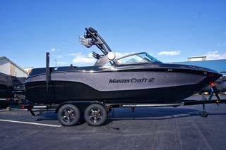 MasterCraft XT23 2025 MasterCraft XT23 boat on trailer, sleek design, parked outdoors under clear blue sky.