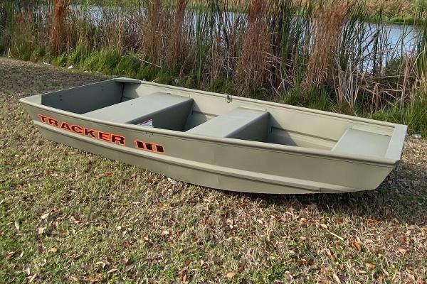 Tracker Grizzly 1036 Utility 2025 Tracker Grizzly 1036 Utility boat on grassy shore near reeds.
