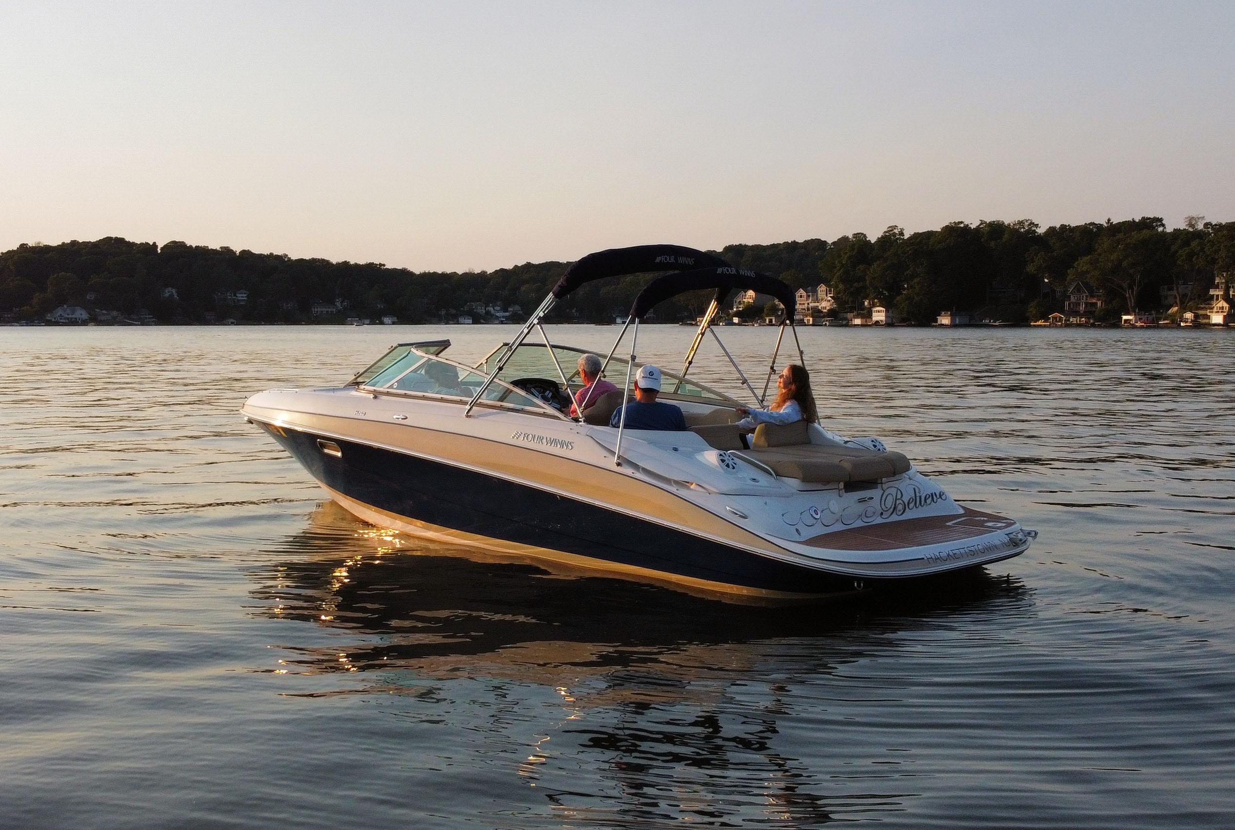 Four Winns H260 2012 Four Winns H260 boat cruising on a serene lake at sunset.