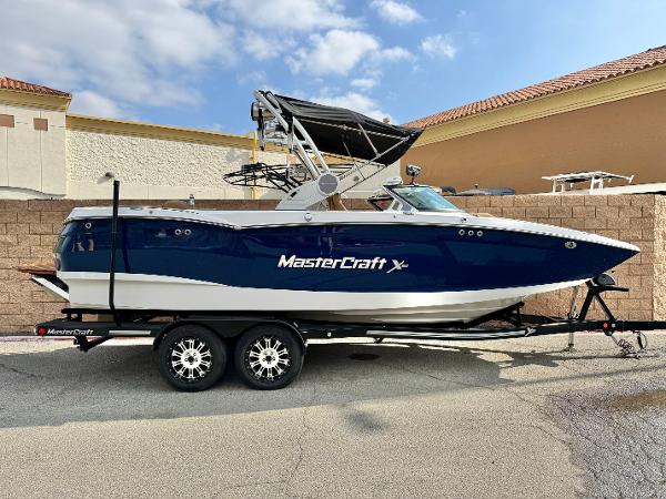 MasterCraft XStar 2022 MasterCraft XStar boat on trailer, parked outdoors, blue and white design.