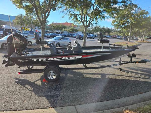 Tracker Pro Team 190 2025 Tracker Pro Team 190 boat on trailer in parking lot, surrounded by trees and cars.
