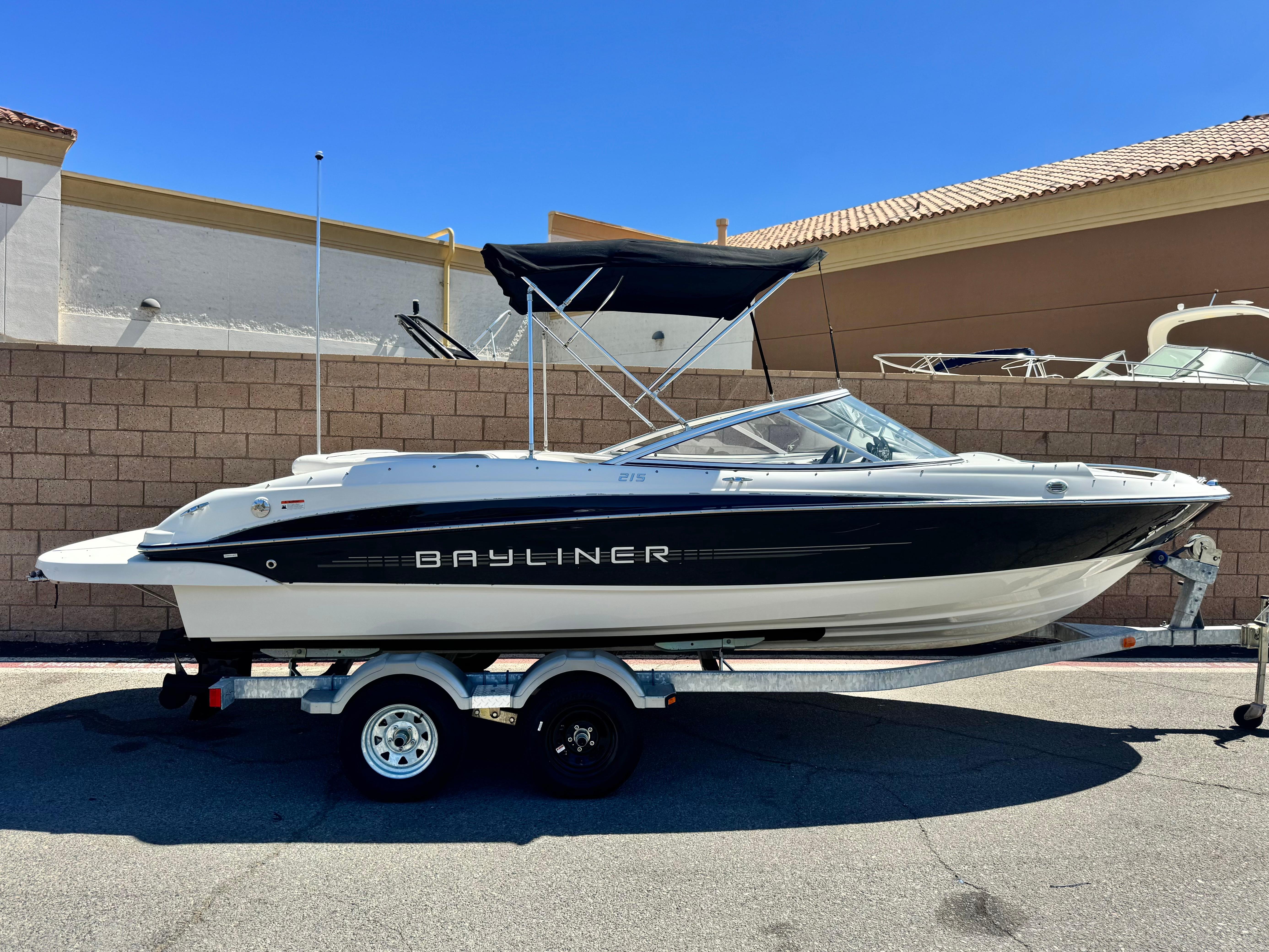 Bayliner 215 2012 Bayliner 215 boat on trailer, parked outdoors under clear blue sky.