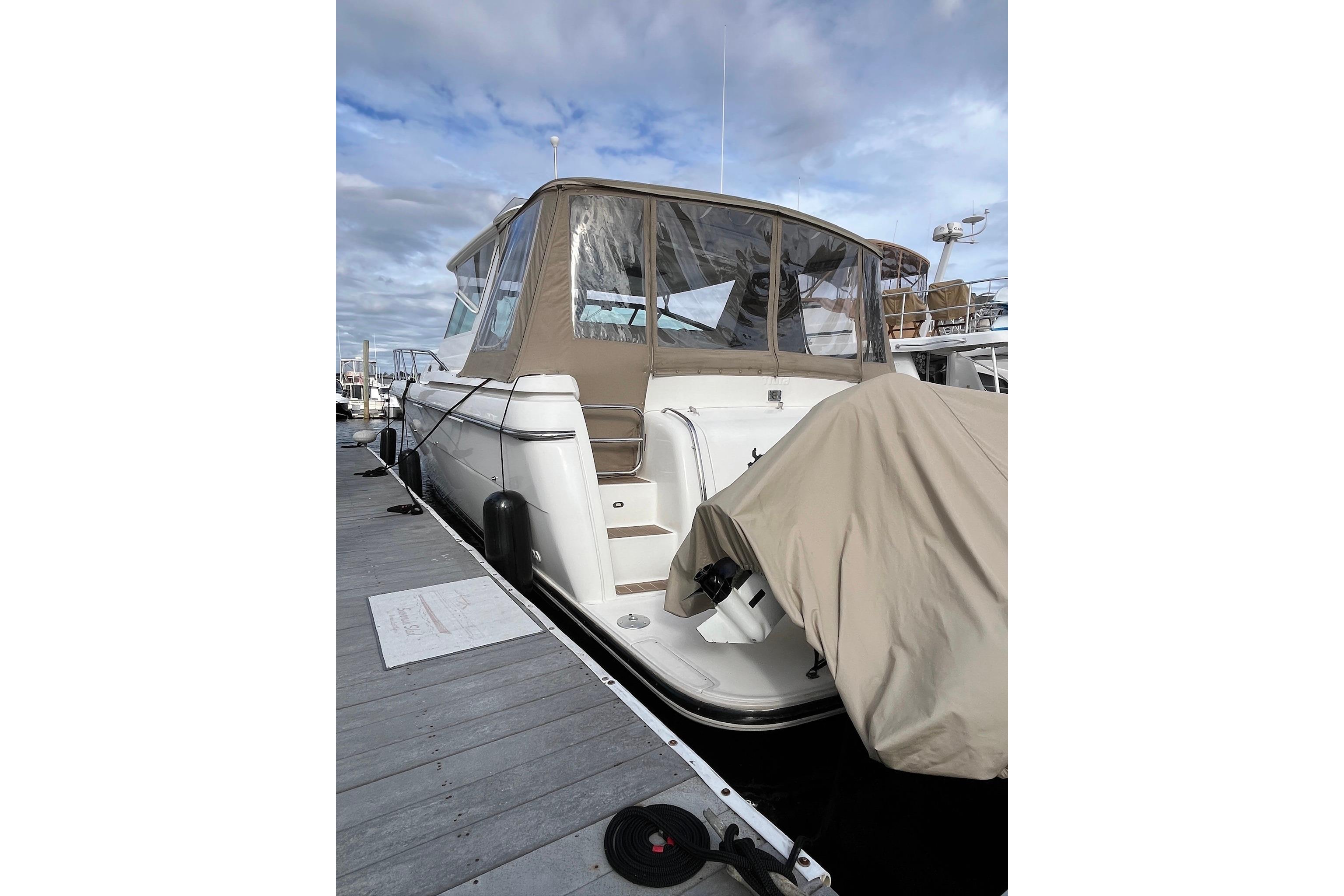 Tiara Yachts 4000 Express 1999 Tiara Yachts 4000 Express docked, featuring beige canopy and covered equipment.