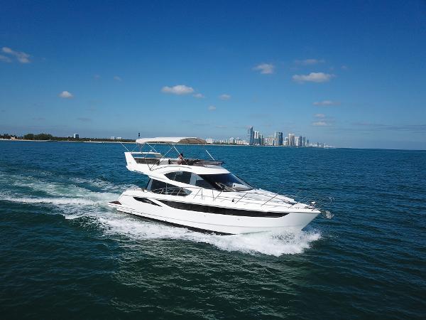Galeon 420 Fly 2016 Galeon 420 Fly yacht cruising on open water with city skyline backdrop.