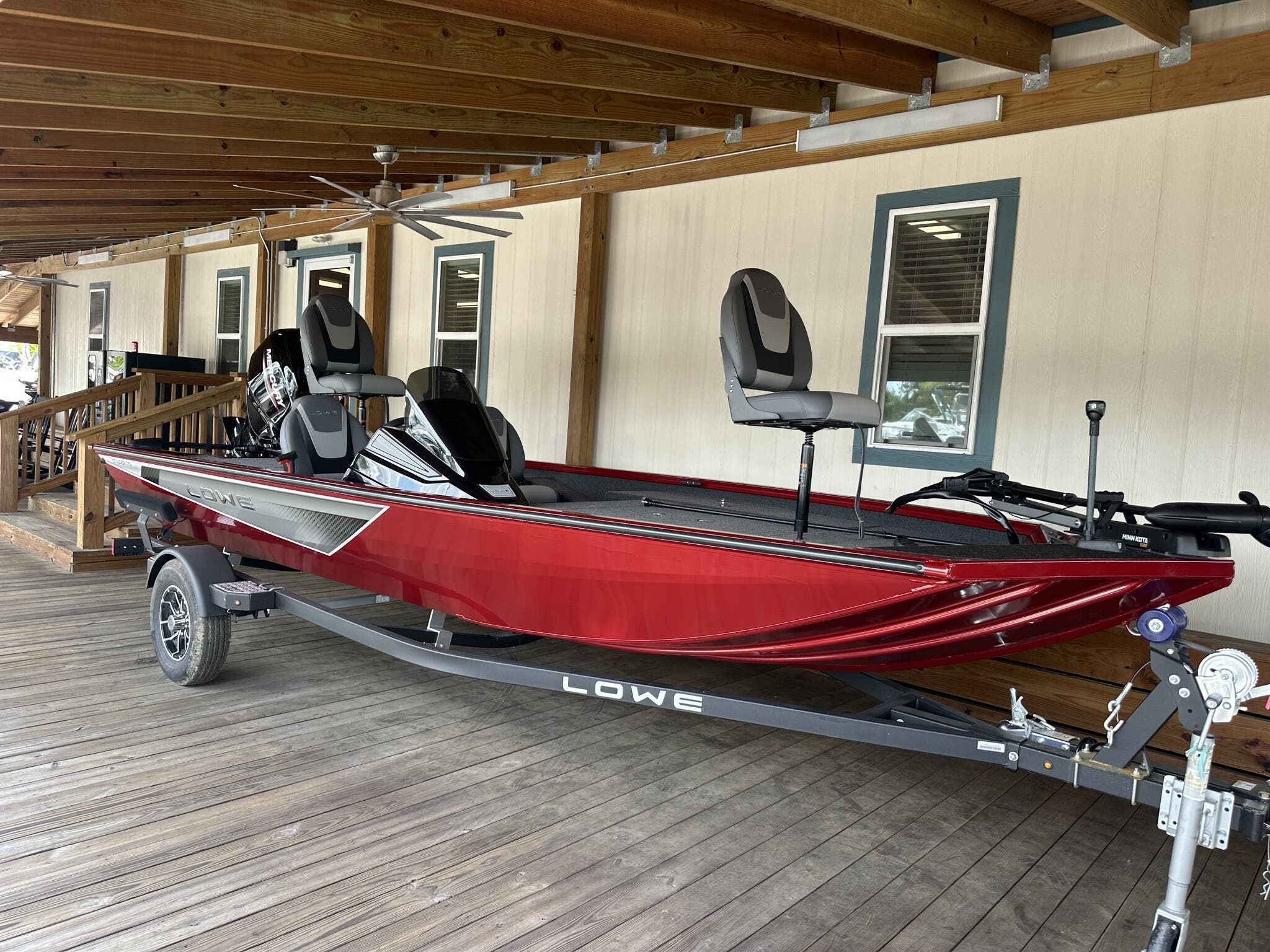 Lowe Stinger 175 2025 Lowe Stinger 175 boat in red on a trailer, parked under a wooden porch.