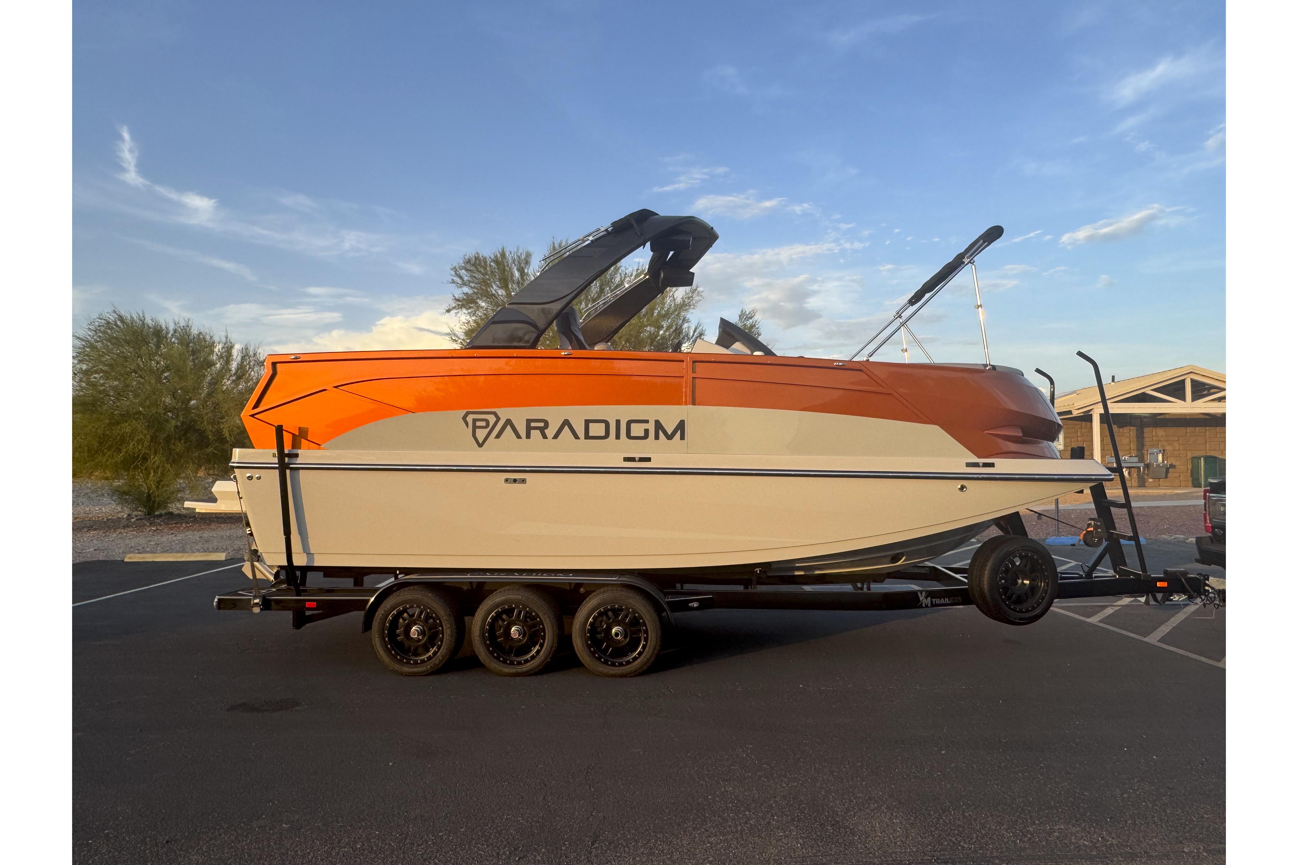 Paradigm 236 Surf 2026 Paradigm 236 Surf boat on trailer, parked outdoors under clear sky.