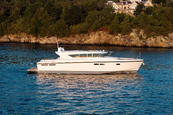 Delta Powerboats 54 IPS 2017 Delta Powerboats 54 IPS yacht on serene water near a rocky shoreline.