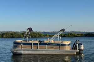 Xcursion 23RFE 2016 Xcursion 23RFE pontoon boat on a calm lake with clear blue sky.