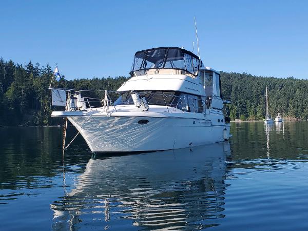 Carver 404 Cockpit Motor Yacht 2000 Carver 404 Cockpit Motor Yacht on tranquil water, surrounded by forested landscape.