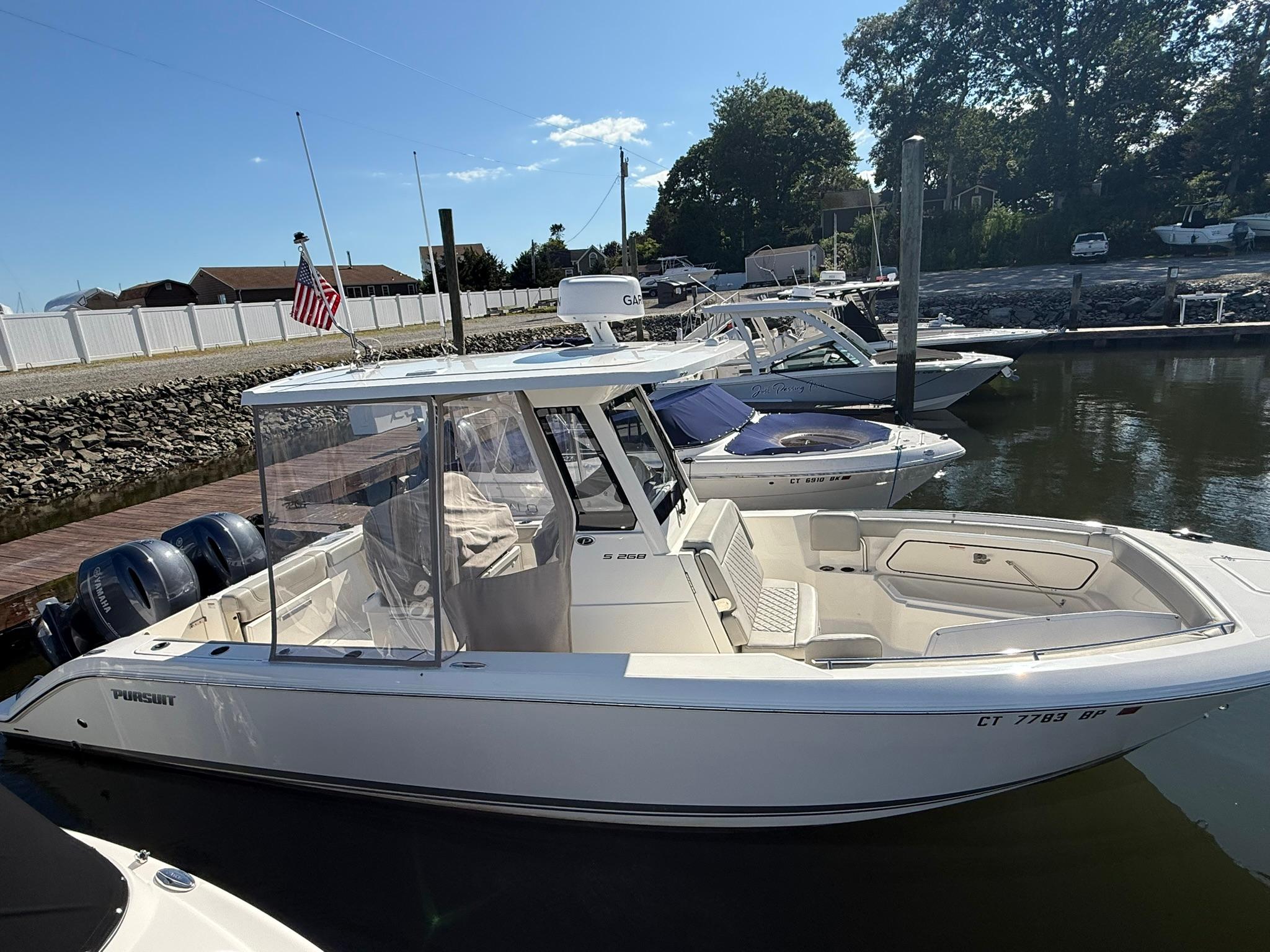 Pursuit S 268 Sport 2023 Pursuit S 268 Sport boat docked in a marina under clear skies.
