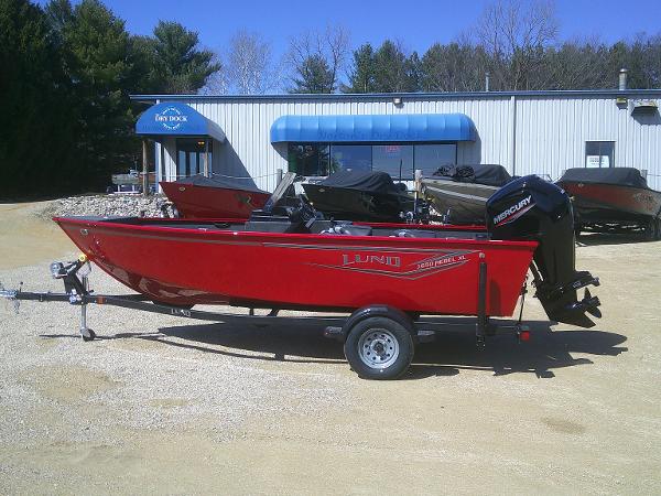 Lund 1650 Rebel XL SS 2024 Lund 1650 Rebel XL SS boat in red, parked outside a dealership.