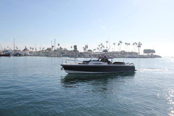 Nimbus T9 Nimbus T9 2024 boat cruising in a sunny marina with palm trees in the background.