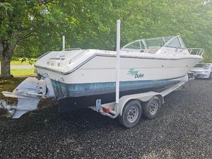 Pursuit 2460 Denali 1999 Pursuit 2460 Denali boat on trailer, parked on gravel, surrounded by trees.