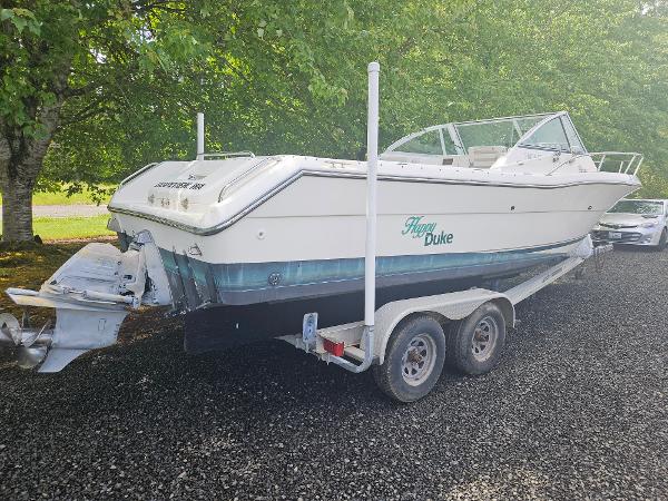 Pursuit 2460 Denali 1999 Pursuit 2460 Denali boat on trailer, parked on gravel, surrounded by trees.