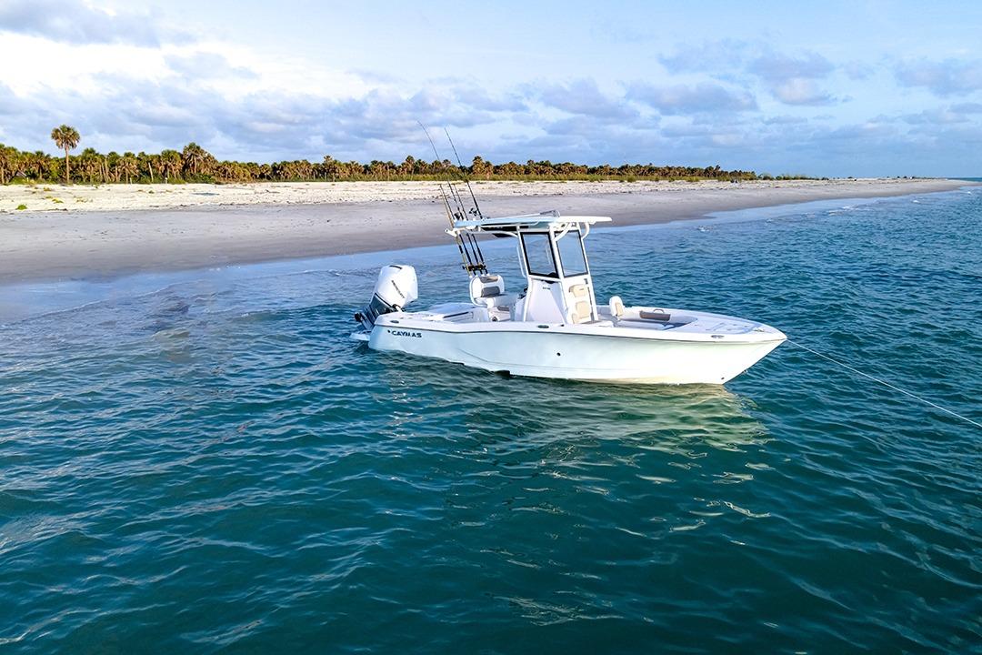 Caymas 24 HB 2026 Caymas 24 HB boat anchored near a sandy beach with clear blue water.