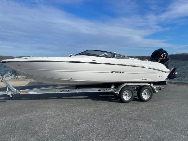 Stingray 23 OSX 2025 Stingray 23 OSX boat on trailer by the water, clear sky background.