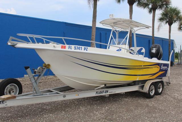 Renegade OSO 2016 Renegade OSO boat on trailer, white with yellow and blue accents, parked near blue building.
