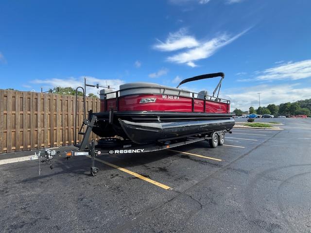 Regency 250 DL3 2024 Regency 250 DL3 pontoon boat on trailer in parking lot under blue sky.
