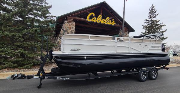 Ranger Reata 223C 2024 Ranger Reata 223C pontoon boat on trailer outside Cabela's store.