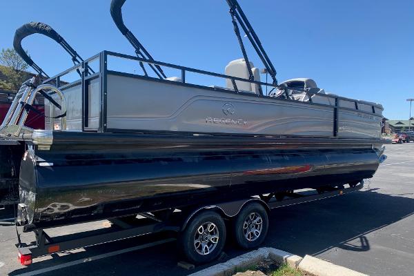Regency R250DL3 2024 Regency R250DL3 pontoon boat on trailer, parked in a sunny lot.