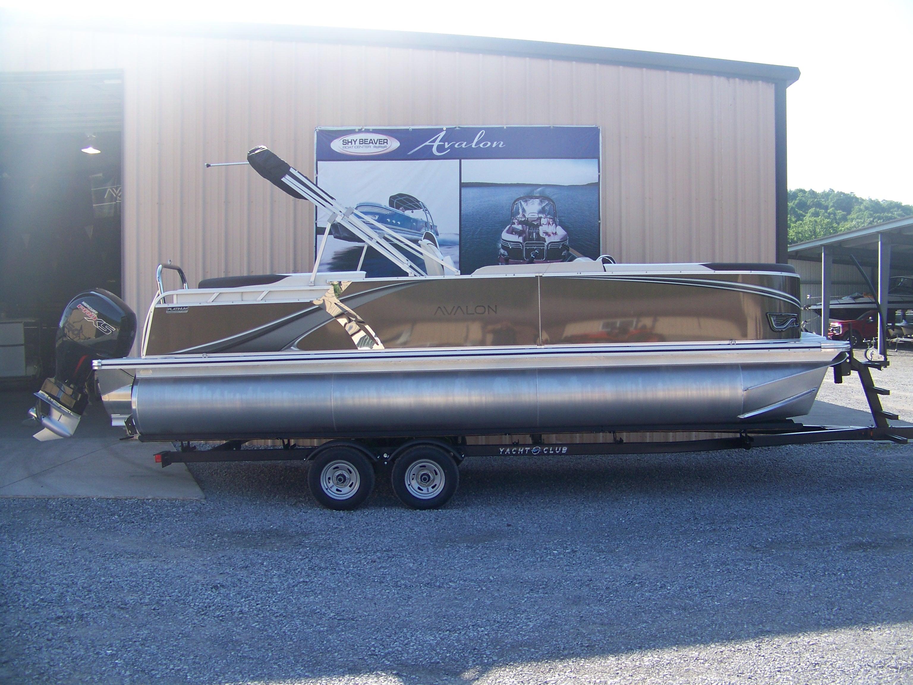 Avalon LSZ ELITE 2025 Avalon LSZ ELITE pontoon boat on trailer outside a showroom.