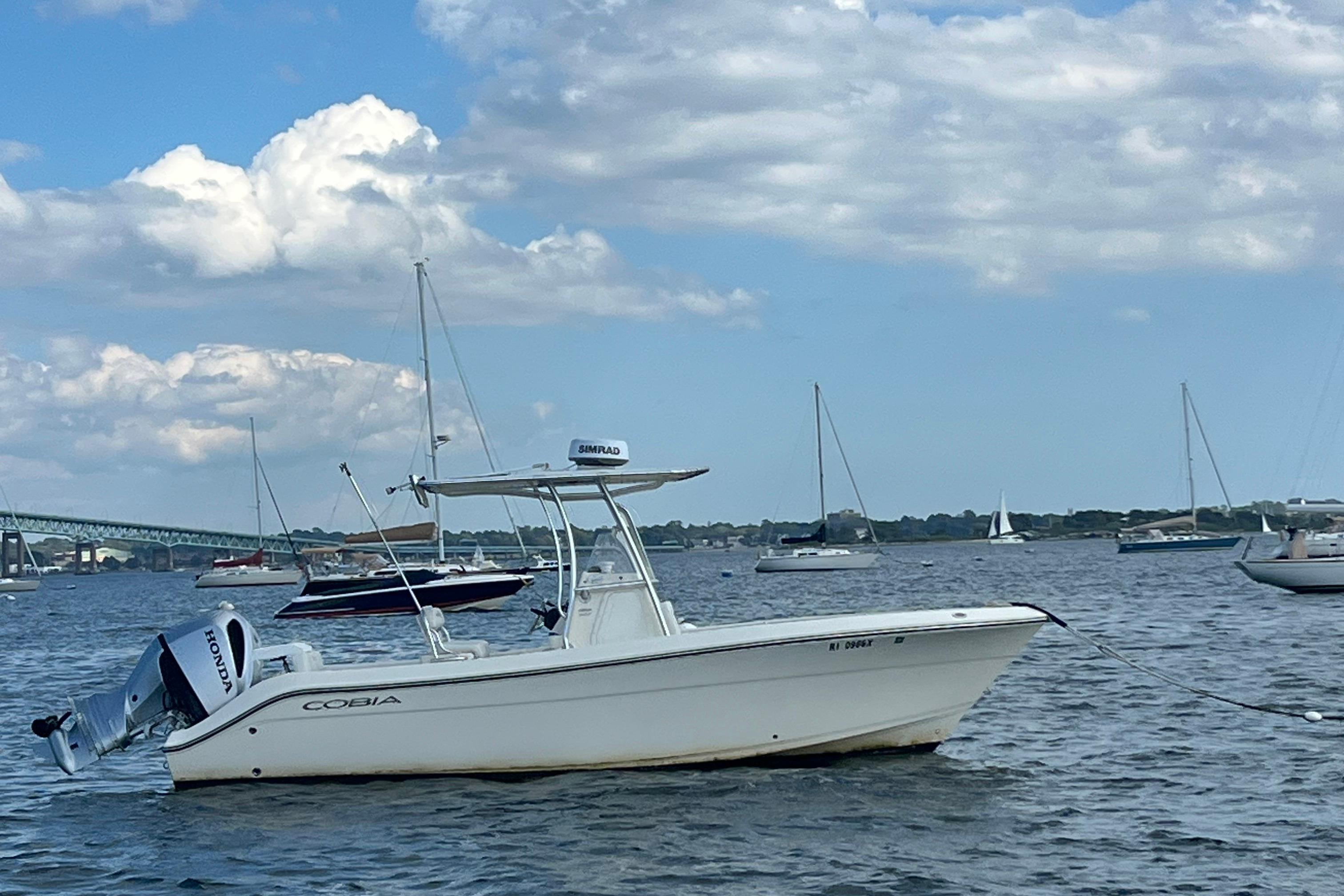 Cobia 237 Center Console 2021 Cobia 237 Center Console boat anchored on a calm, scenic waterway.