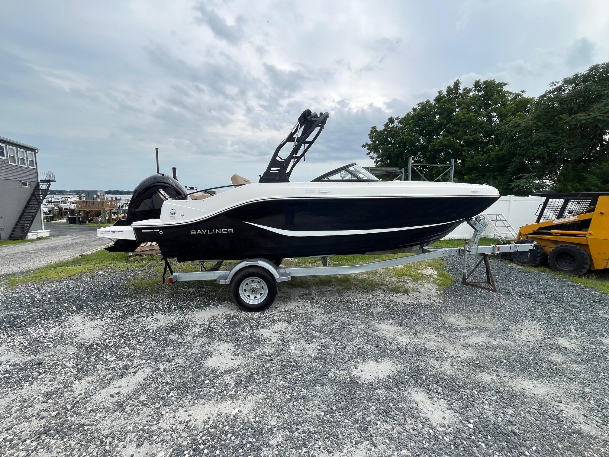 Bayliner D20 2025 Bayliner D20 boat on trailer, parked outdoors on gravel, under cloudy sky.