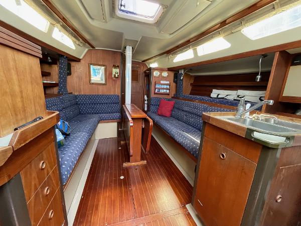 C&C MK III Sloop 1987 C&C MK III Sloop interior with wood finish, blue seating, and compact kitchen area.
