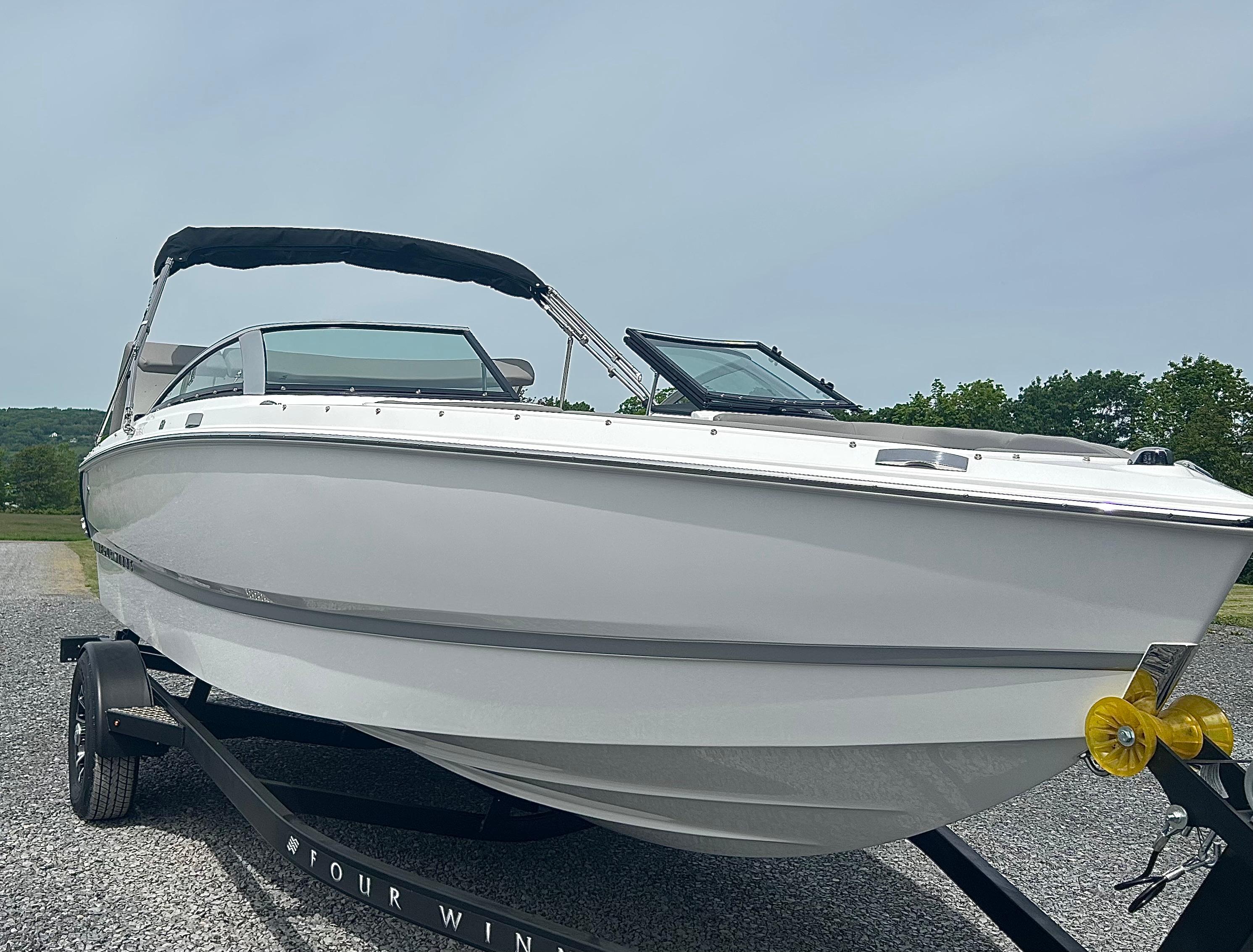 Four Winns H1 Freedom 2025 Four Winns H1 Freedom boat on trailer, sleek design, outdoor setting.