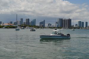 Axopar T-Top 2015 Axopar T-Top boat cruising in a city harbor with skyline backdrop.