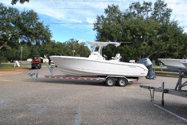Edgewater 245CC 2023 Edgewater 245CC boat on trailer in parking lot, surrounded by trees.