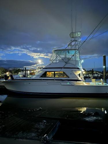 Bertram 43 Convertible 1989 Bertram 43 Convertible yacht docked at twilight, under a cloudy sky.