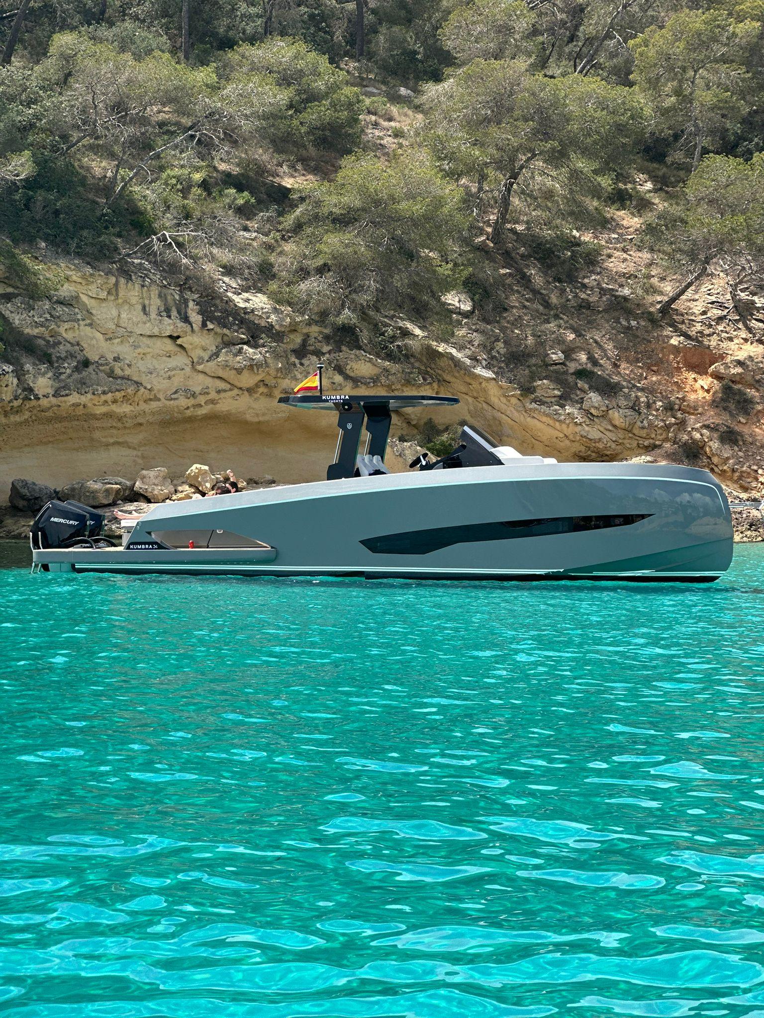 Kumbra 34 A sleek 2026 Kumbra 34 yacht on turquoise water near a rocky shoreline.