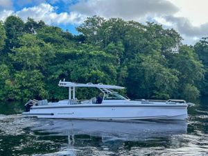 Axopar 37 Sun Top 2024 Axopar 37 Sun Top boat cruising on a river with lush green trees in the background.