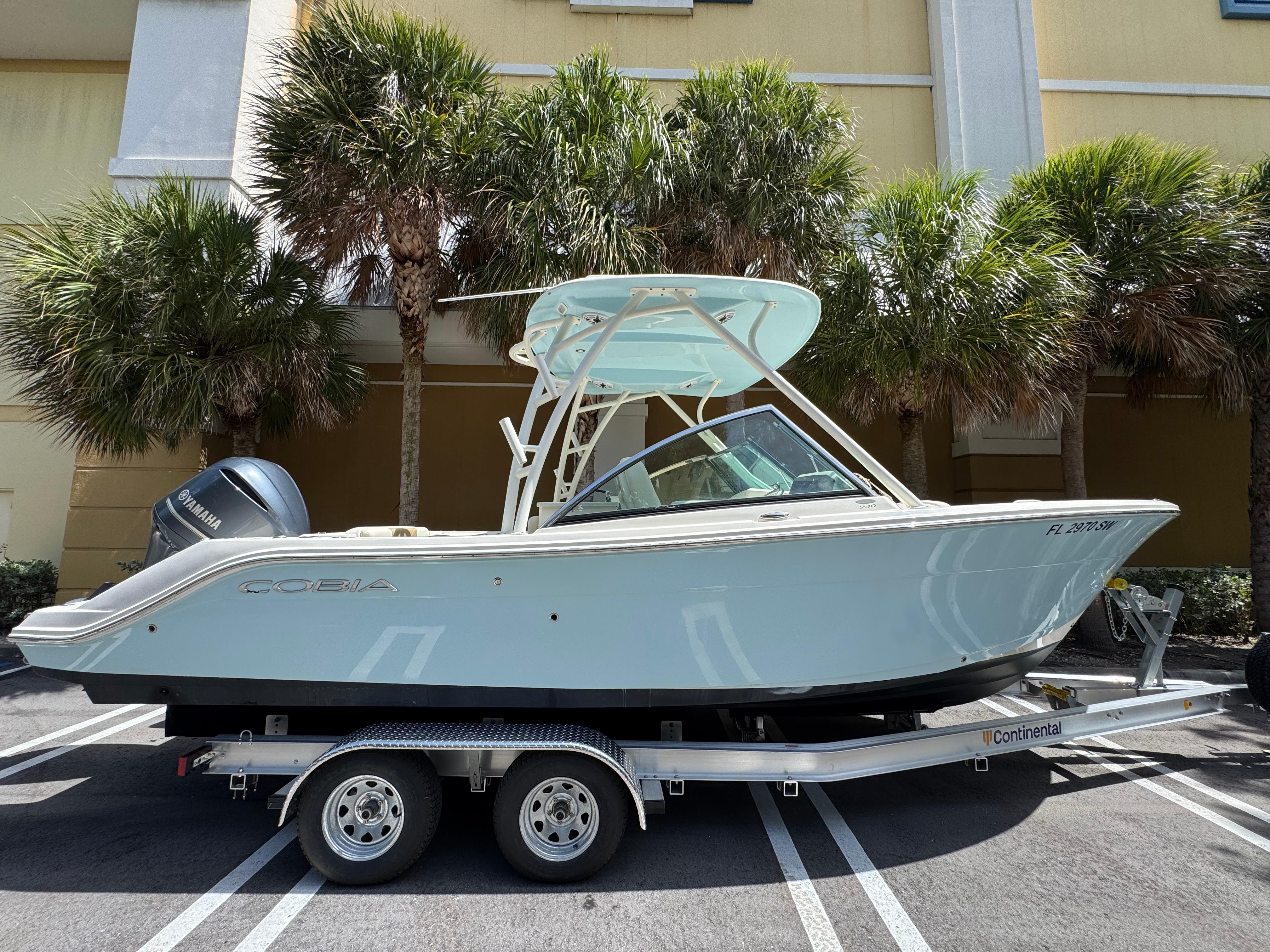 Cobia 240 Dual Console 2021 Cobia 240 Dual Console boat on trailer, parked near palm trees.