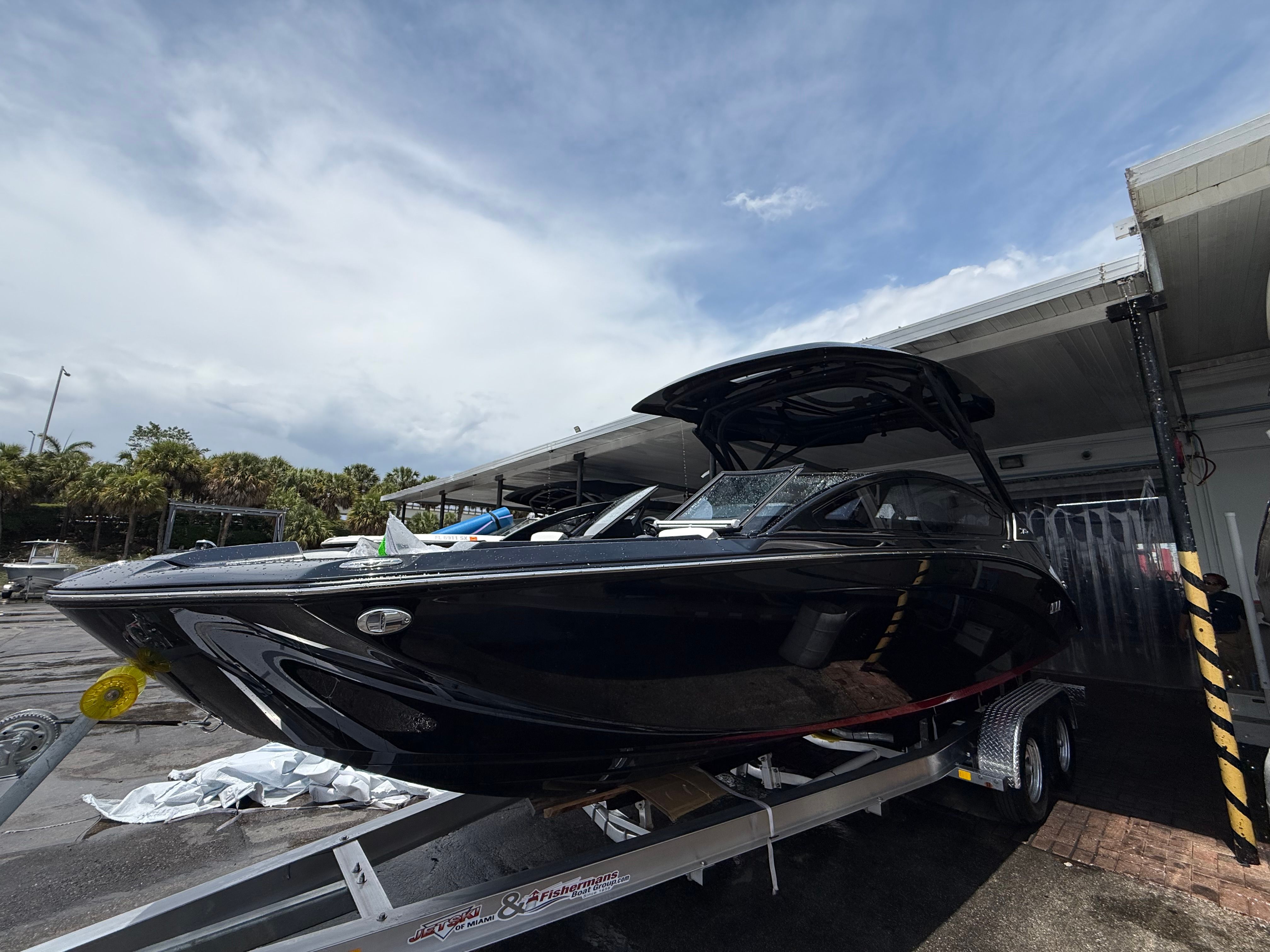 Yamaha Boats 275SD 2025 Yamaha Boats 275SD on trailer, sleek black design, parked outdoors under cloudy sky.
