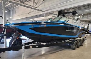 MasterCraft X26 2018 MasterCraft X26 boat on trailer in showroom, featuring sleek black and blue design.